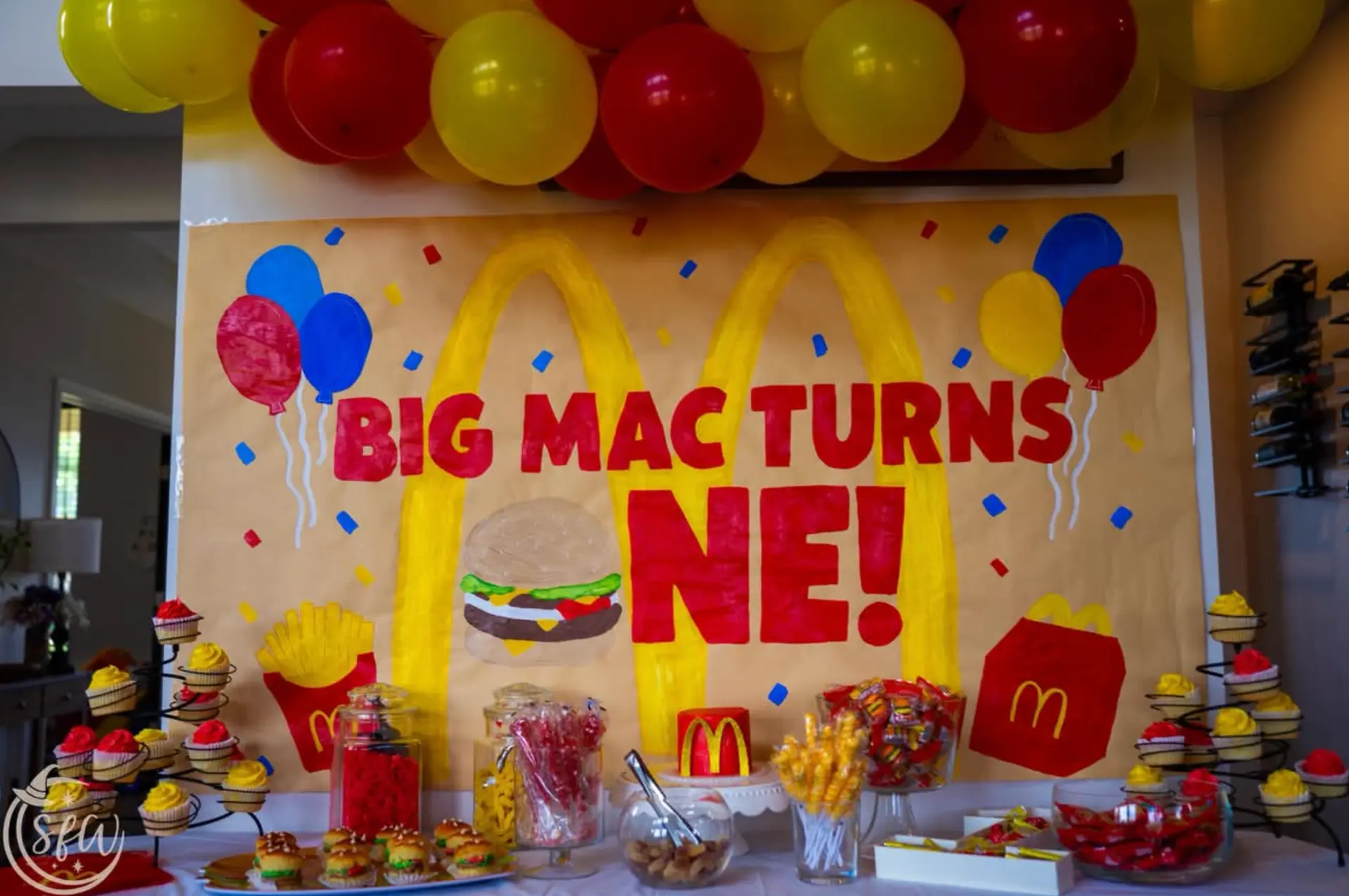 Custom painted birthday backdrop with balloon garland and styled dessert table